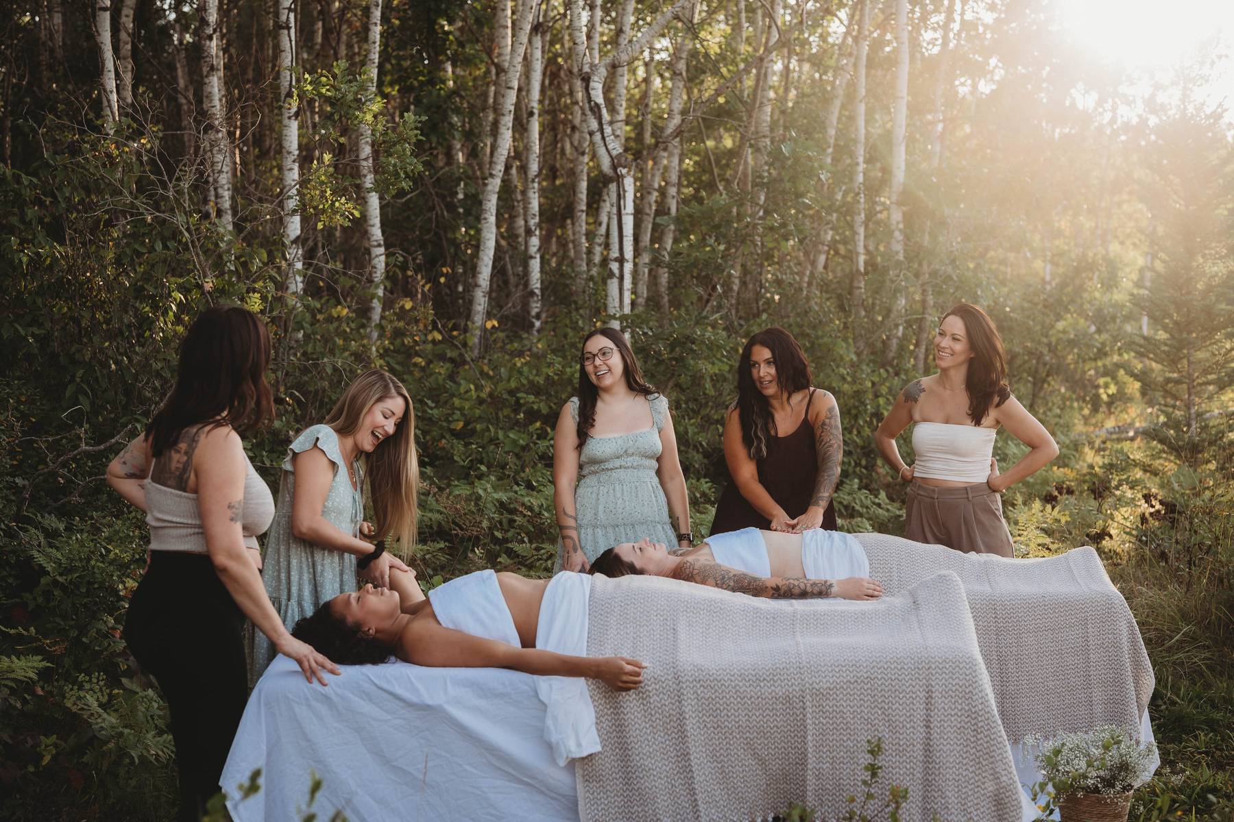 The Contour Culture team gathered around massage tables in a birch grove at golden hour